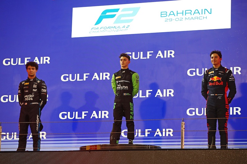 Jak Crawford, Zane Maloney et Pepe Marti sur le podium de la course sprint à Bahrein, mains dans le dos en écoutant les hymnes.