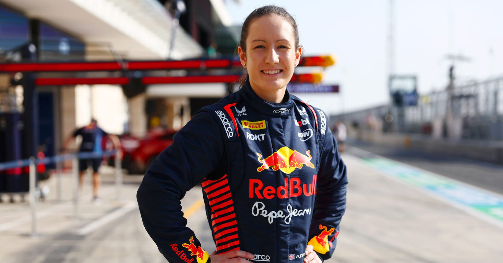 Alisha Palmowski pose dans la voie des stands avec une combinaison Red Bull.