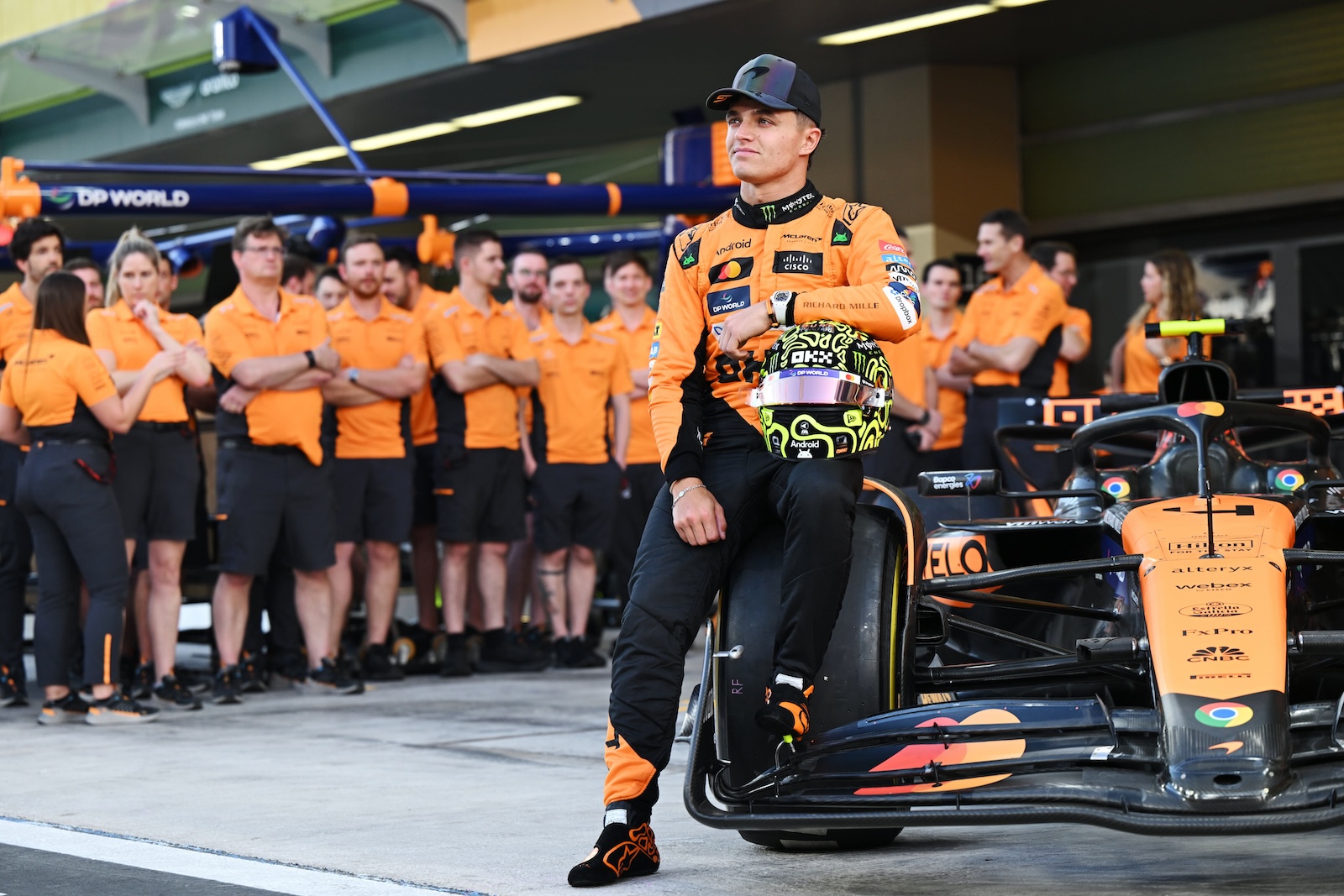 Lando Norris posant avec son casque sur la McLaren