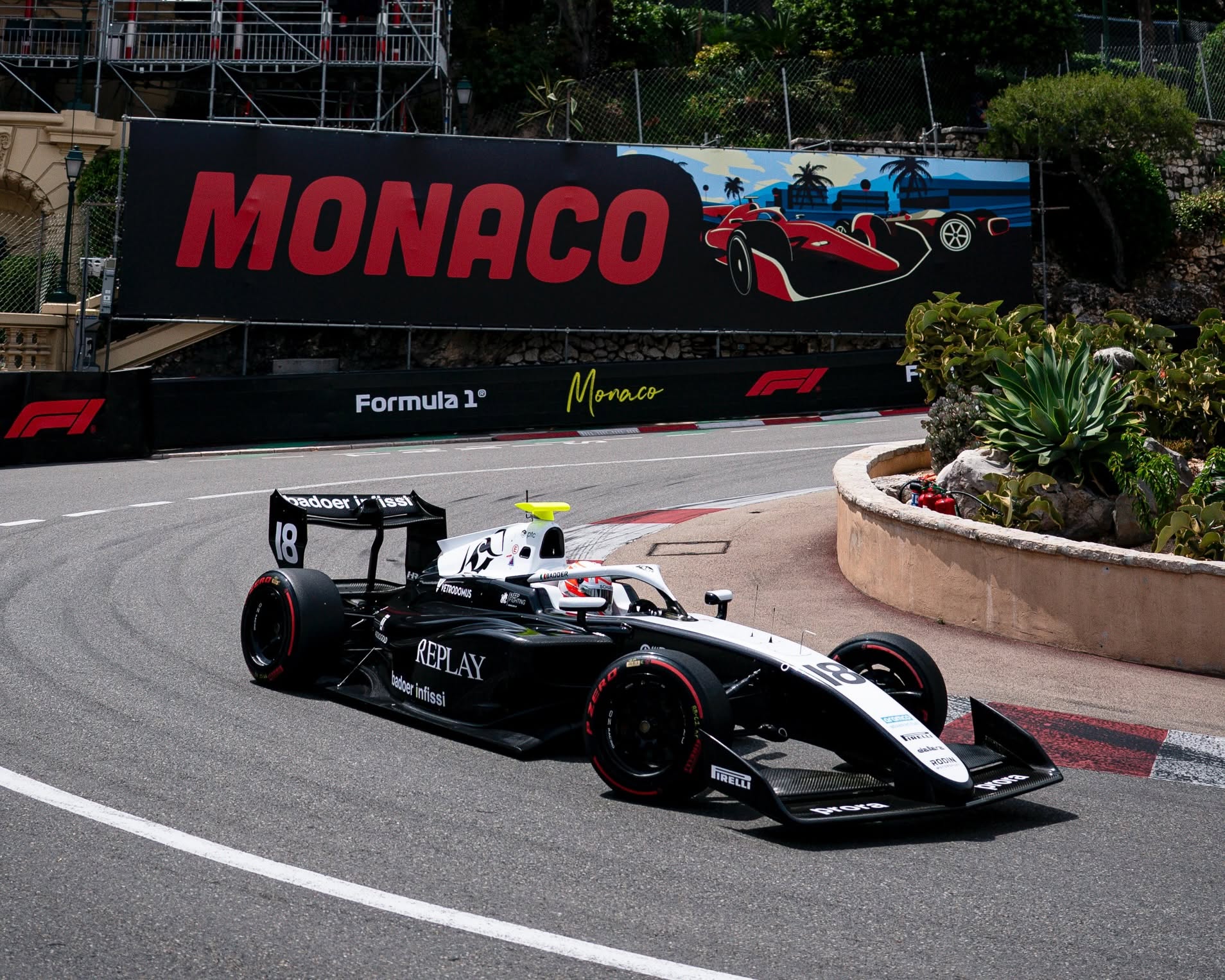 Brando Badoer dans sa monoplace dans le virage avec Monaco écrit en rouge en arrière plan